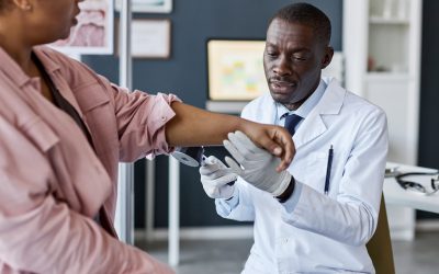 Portrait of adult African American man as doctor examining patient during consultation in clinic and looking at skin copy space